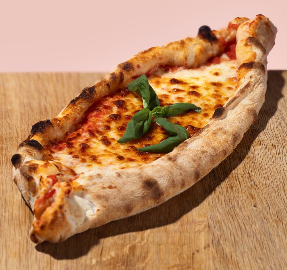 Frisch gebackene Pide mit Belag auf Holztisch